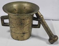 Side view of brass mortar and pestle showing form and patina