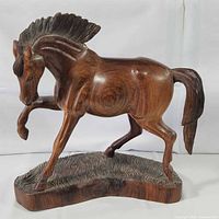 front left view of carved wooden horse on base