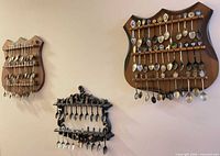 Three wall-mounted racks filled with souvenir spoons
