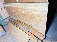Stack of five plywood sheets with bundled flooring planks and trim pieces