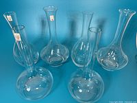 Front view of six clear glass decanter vases