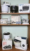 Overall lot showing mixer, juicer, accessories and boxes on shelving