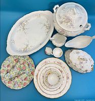 Grouped overhead view of all porcelain items and tongs on blue background
