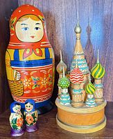 Large nesting doll, miniature pair and cathedral music box grouped together
