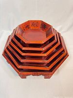 Stacked view of all seven octagonal trays showing lacquer finish and hand-painted motifs