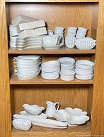 Shelved view of majority of porcelain pieces showing stacks of ramekins, gratin plates, bowls and boxed items