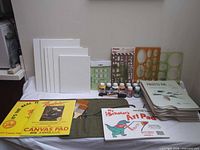 Overview of all items on table: canvas panels, pads, paints, palettes, stencils, brushes