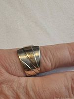Ring front view on finger showing sculptural sterling body and gold accent