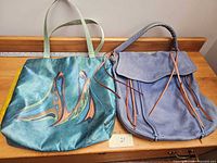Front view of teal satin printed tote and blue leather hobo bag