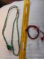 Full view of emerald necklace and ruby bracelet with ruler showing scale