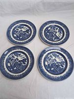 Top view of four matching blue and white Willow pattern plates