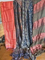 Four shawls hanging side by side showing overall colors and patterns