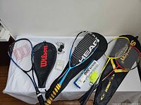 Five racquets, covers, balls and shuttlecock tube displayed on table