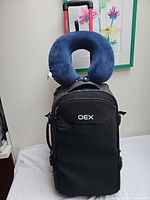 Front view of OEX suitcase with attached neck pillow