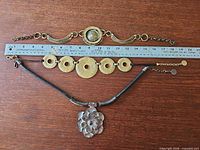 Three necklaces laid next to ruler for scale