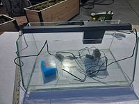 Full view of glass aquarium with LED light bar, filter, cords and boxed cartridges inside