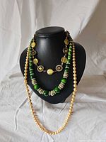 Overall view of three necklaces on bust