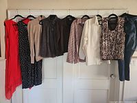 Nine garments hanging on door showing variety of styles and colors