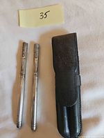 Two sterling silver pens and black leather pouch laid out