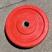 Front view of red 45 LB bumper plate showing weight marking and center sleeve
