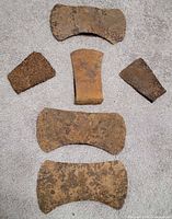six loose axe heads laid out on carpet