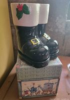 Front view of ceramic Santa boots planter on decorative box