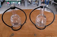 Two glass bottles in wrought iron stands on tabletop