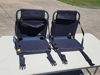 Front view of two folded-open GCI Outdoor stadium seats on table