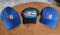 Front view of three hats showing team logos and colors