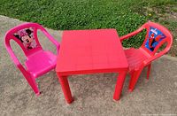 Square red plastic kids table with two character chairs outdoors