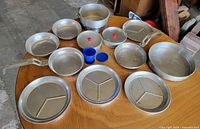 All 15 pieces laid out showing variety of pots, pans, plates, bowls, plastic accessories