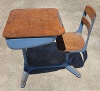 Three-quarter view of desk showing wood top, seat back and metal frame
