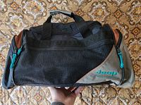 Front view showing logo, mesh pocket, top handles