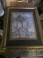 Front view of framed artwork with ornate gold frame and black mat