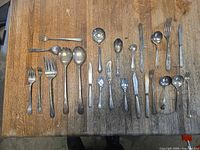 Full view of all 24 assorted silver-plated flatware pieces on table