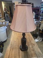 Full view of lamp with pink shade on wooden surface