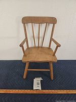Front view of wooden child chair showing spindle back and armrests