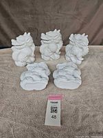 Three upright and two reclining white ceramic dragon figurines on towel