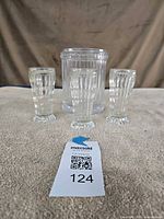 Front view of ribbed MMA jar with lid and two of three fluted glasses