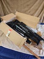 Cardboard box full of black metal drawer slides