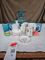 Group shot of entire lot showing pitcher, tumblers, mugs, teacup, saucer and shakers