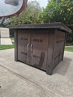 Front angled view of square metal propane fireplace showing cabinet doors and rust patina