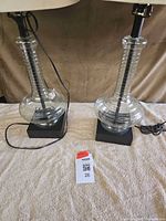 Two matching glass table lamps without shades showing clear bodies and bases