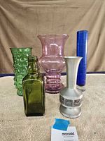 Group shot of five items: three glass vases, one glass bottle, one pewter vase