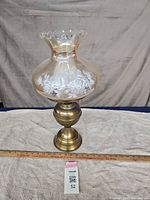 Full view of brass lamp with floral glass shade