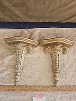 Pair of wall sconces lying flat showing shelf tops and bracket designs
