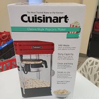 Photo of the unopened retail box of the Cuisinart Classic-Style Popcorn Maker CPM-28C with front label showing key product features such as 500 watt heating, party capacity of up to 10 cups, and easy cleaning.