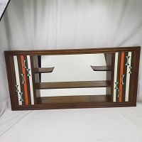 Full frontal view of the mid-century modern curio shelf with mirror and geometric side designs.
