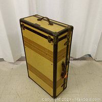 Full view of Art Deco 1920s Mendel Tourist steamer wardrobe trunk standing upright, showing cream and brown striped pattern, metal corner reinforcements, leather handle on top.