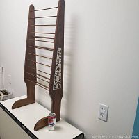 Left side angle view of wooden magazine rack showing overall form and tiled inlay on side panel.